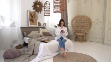 Slow Motion Relaxed young woman using cell phone in bed