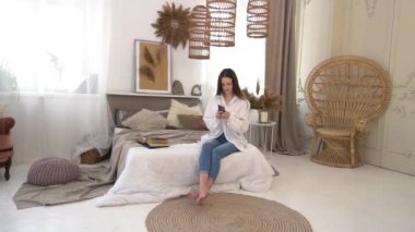 Slow Motion Beautiful young brunette woman using a phone in her bedroom.