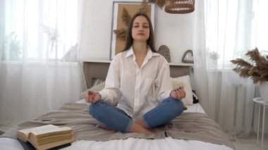 Slow Motion Sakin esmer yatak odasında yatakta yoga yapıyor.