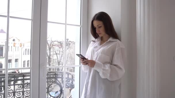Slow Motion Young Woman Phone Looking Out Window Home — Vídeo de stock