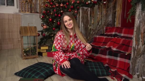 Κορίτσι Ένα Κόκκινο Φόρεμα Κάθεται Κοντά Ένα Χριστουγεννιάτικο Δέντρο Ένα — Αρχείο Βίντεο