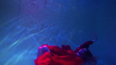 Slow Motion Dancing woman under the water in a pool in a red dress.