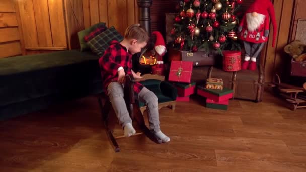 Mały Chłopiec Siedzi Koniu Bujanym Domu Przed Choinkami — Wideo stockowe