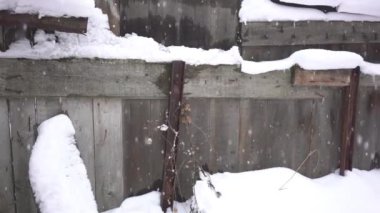4k Snow-covered wooden fence of an abandoned building.