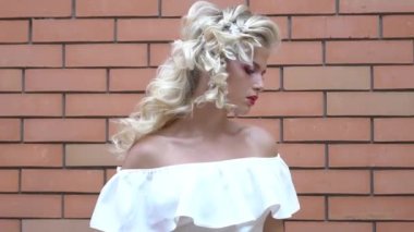 Bride in white wedding dress in the background of brick wall