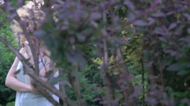 Slow Motion Curly brunette woman with afro hairstyle posing in garden.