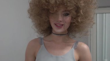 Slow Motion Young woman with beautiful curly hair on gray background