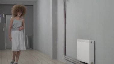 Young smiling woman with curly hair outdoors.