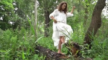 Walking Beautiful young woman forest nymph in white dress in evergreen wood
