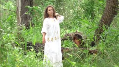 Beautiful young woman in white dress at the forest in summer.