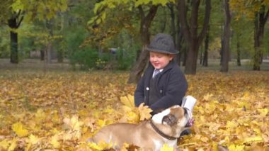 Slow Motion 'daki çocuk güz parkında dost canlısı köpek bulldog hayvanıyla oynuyor.