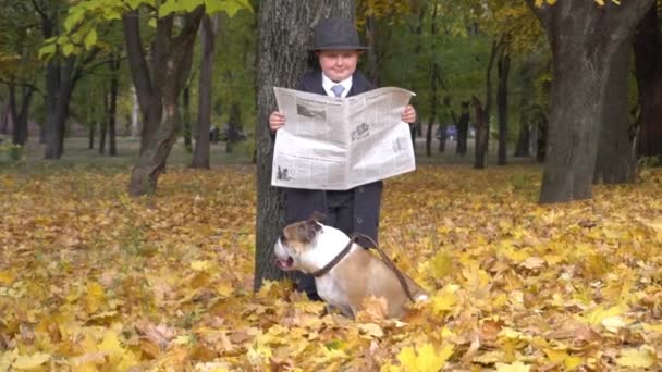 Slow Motion Little Newsboy Reading Newspaper Dog Bulldog Autumn Park — ストック動画