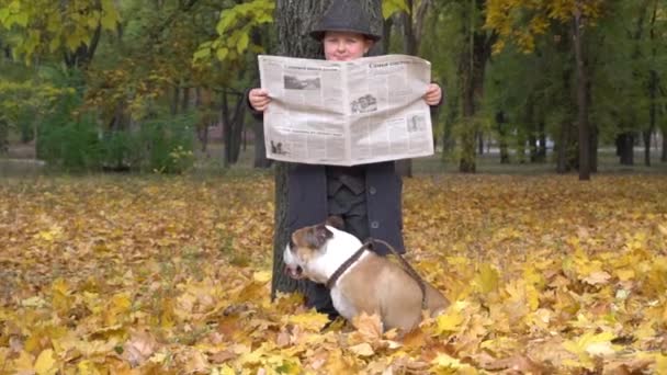 Осень Мальчик Черном Костюме Парке Читает Газету Собакой Бульдогом — стоковое видео