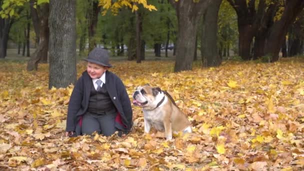 Slow Motion Boy Black Suit Sits Lawn Bulldog Autumn Park — Vídeo de Stock