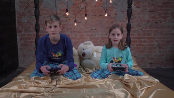 Dos Niños Hermano Hermana Están Sentados Una Cama Jugando Videojuegos — Vídeos de Stock