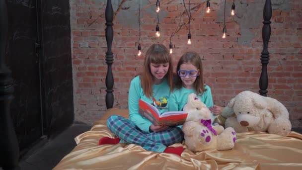 Two Girl Sisters Friends Pajamas Reading Book Lying Bed Home — Stockvideo