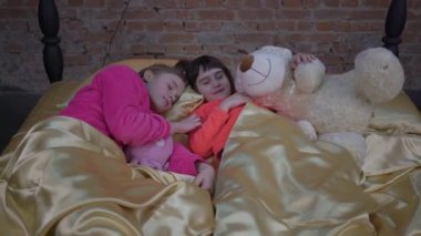 4K Sleepy kids in pajamas having rest on comfortable bed