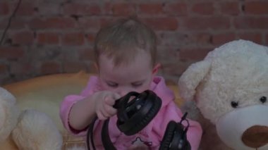 gülümseyen bebek kulaklık ile oynarken bir yatakta oturma