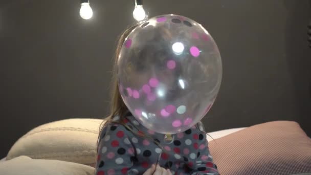 Lita Jente Sitter Seng Leker Med Ballong – stockvideo