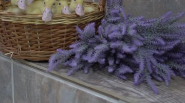 Yavaş hareket eden sarı ördek yavruları çiçeklerle dolu bir sepette oturuyorlar.