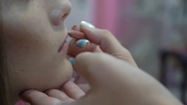 Closeup of client lips getting makeup from professional makeup artist 