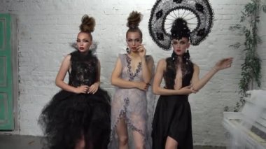 Three girls in vintage style in dresses with creative hairstyle