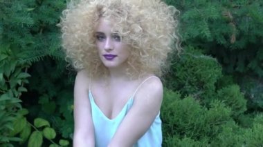 Beautiful young woman with curly hair afro hairstyle posing in a botanic garden
