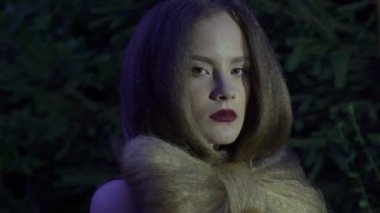 Portrait of dangerous fantasy woman in dark red evening dress next to a tree