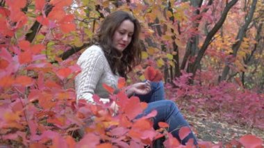 Slow Motion Portrait of happy young woman with leafs in front of foliage