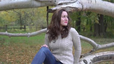 Slow Motion Güzel esmer Sonbahar parkında bir ağaçta oturuyor