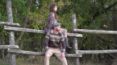 Slow Motion young couple embracing and looking at side while sitting on fence