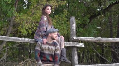 Bir çift erkek ve kız tahta bir çitin ve çimenli bir arazinin yanında kavga ederler.