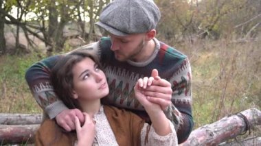 Birbirine aşık Ağır Çekim Çifti bir kütüğün üzerinde oturuyor. Gün batımı. Orman.
