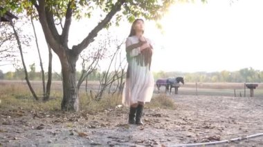 Gün batımında çiftlikte atların yanında poz veren güzel genç bir kadın. 