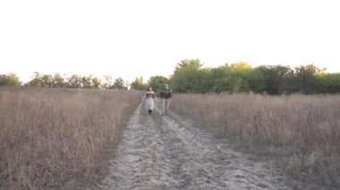 Slow Motion couple of young men and women are running merrily through a field