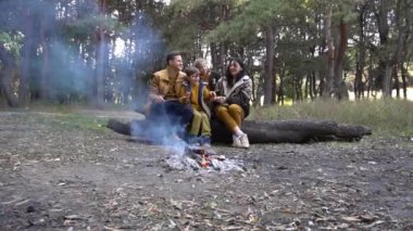 Neşeli ebeveynler, ormanda ateşin yanında çocuk sahibi.