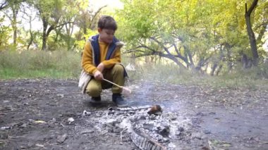 Düşünceli bir çocuğun portresi kamp ateşinin yanında tek başına mutlu tatiller geçiriyor.