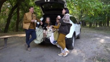 Happy Young Family Enjoying Weekend Sitting on the Trunk of the Car
