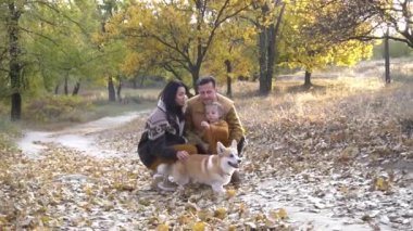 Happy family having fun with their dog outdoors in forest.