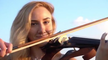 Genç bir kadının yakın plan portresi buğday tarlasında keman çalıyor..