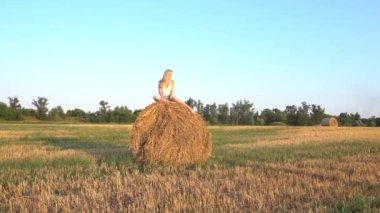 Slow Motion young female sitting on a haystack