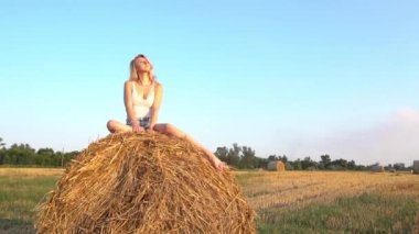 Slow Motion young beautiful woman near large haystack in an empty field