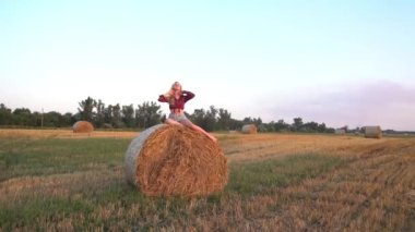 Portrait of a charming young girl in a sitting on a haystack.