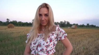 Kırsalda saman balyalarının yanında bir kız. Samanlıkların arka planındaki kız