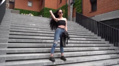 Slow Motion Stylishly dressed woman posing on the stairs of a modern building