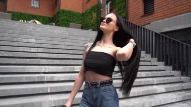 Ağır çekim güzel kız büyük merdivenlerde poz veriyor.