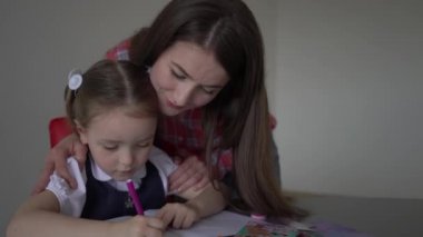4k Young caucasian mother helping her daughter schoolgirl with homework