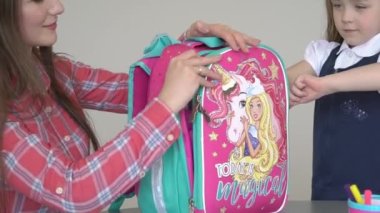 Closeup on child with workbooks and backpack packing for school at home