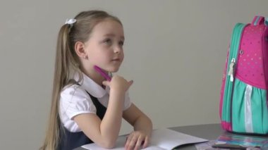 Schoolgirl girl writes in a notebook the teacher's assignment at home