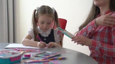 Slow Motion Caring young mom and small 7s daughter make homework together.